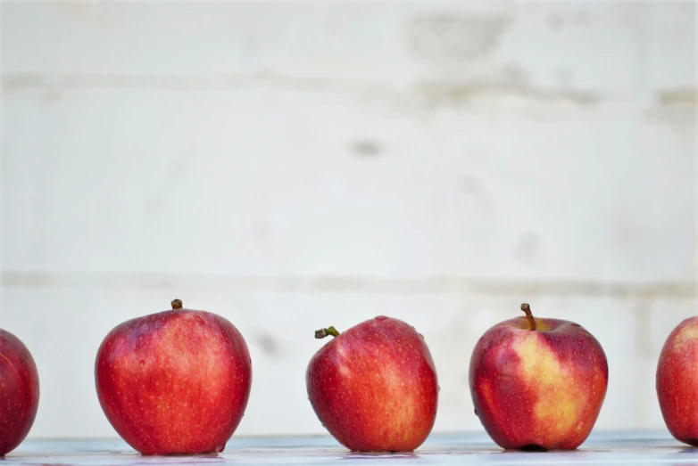 five red apples sit together against the white backdrop