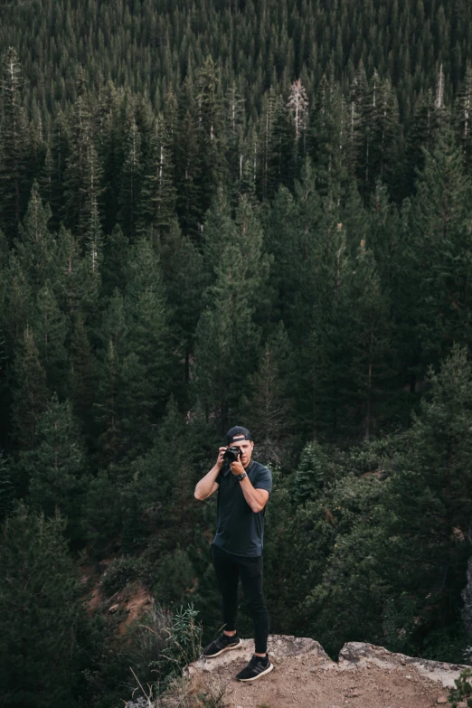 a man taking a po of the tree covered mountain