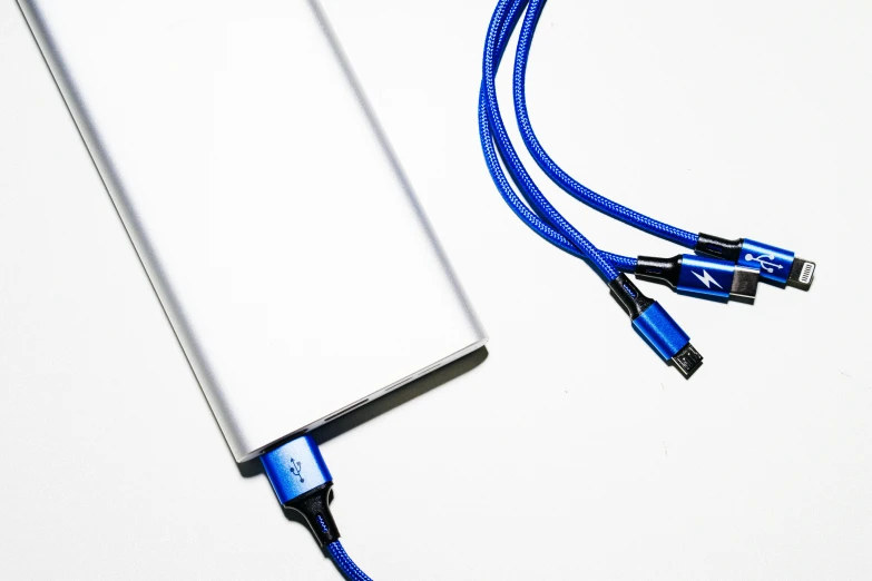 a white electronic device being held up to show the cable that is plugged into it