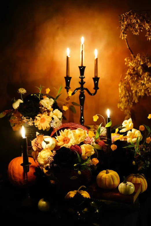 a table with flowers and candles sits near some fake pumpkins