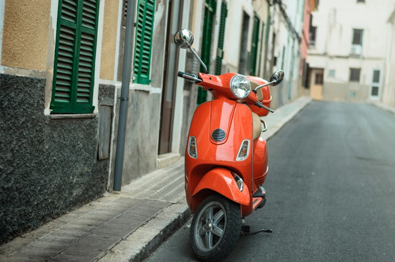 a red moped sitting on the side of a street