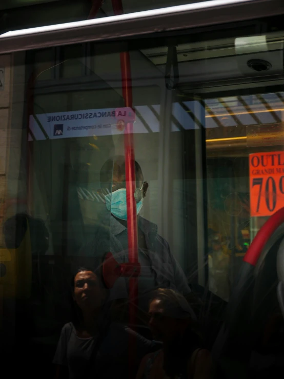 two men are wearing masks as they stand on the bus