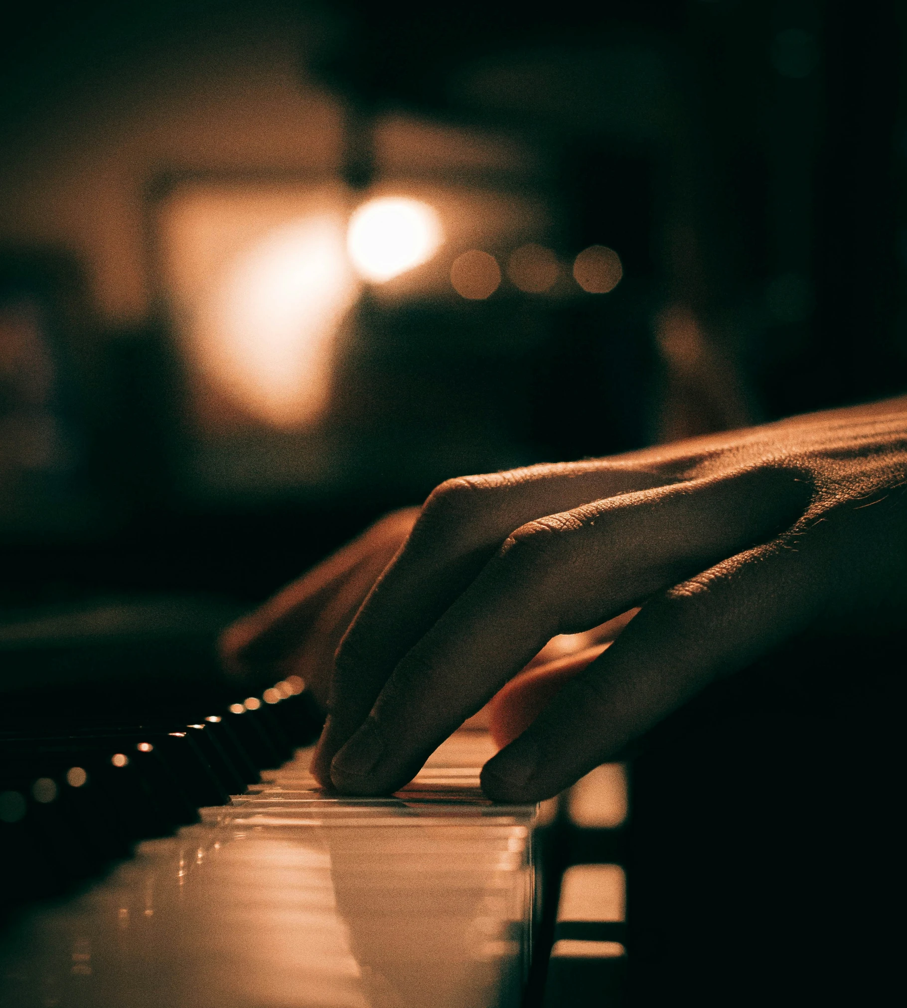 two hands on a piano in the dark