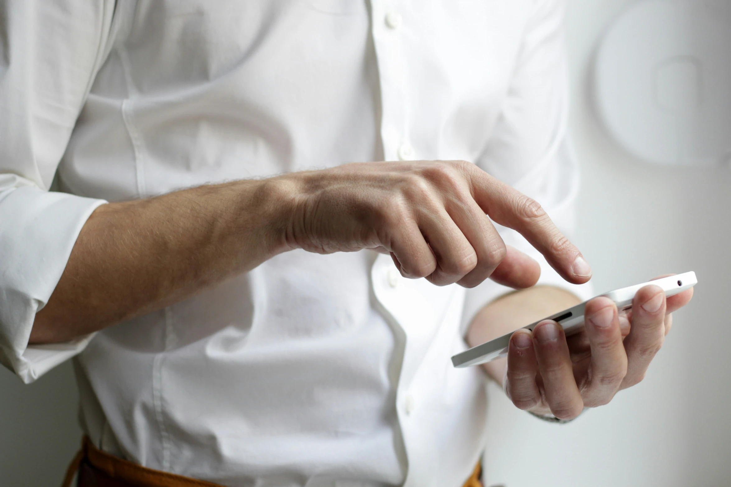 a person's hands holding a white smart phone and a stand