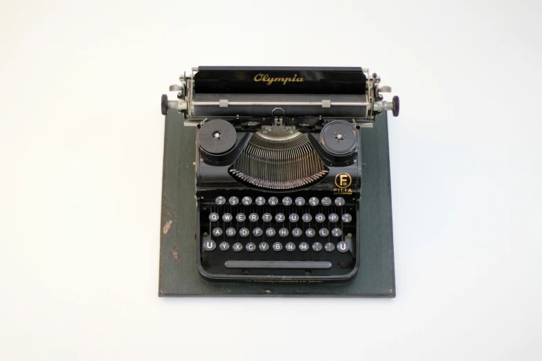 the black antique typewriter is set up against a white background