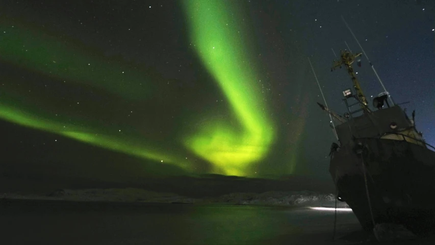 a ship with aurora lights and an unknown object in the background