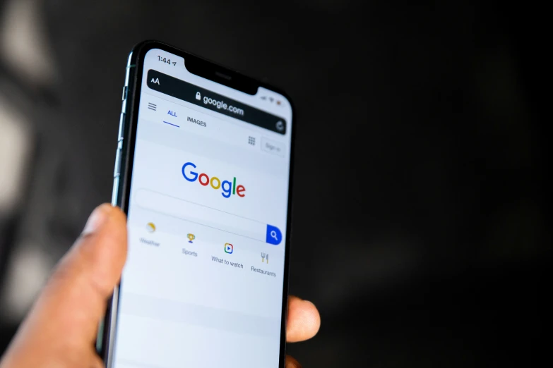 someone holding up their cellphone displaying the google logo
