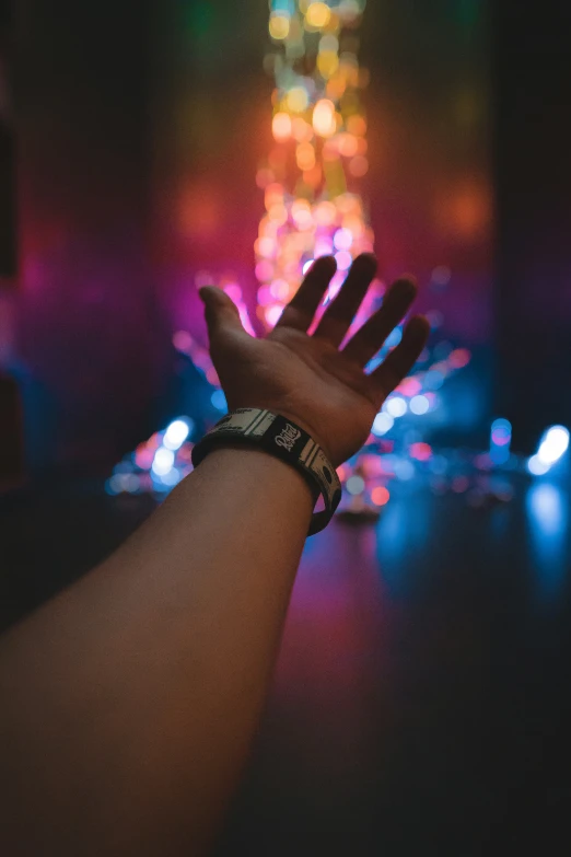 a hand is holding out the light in front of colorful lights