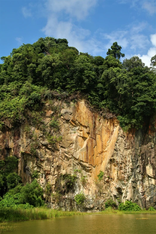 a boat on a small river next to the side of a rocky cliff