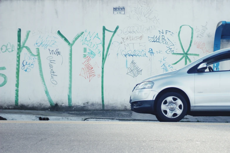 a car is parked by a graffiti wall