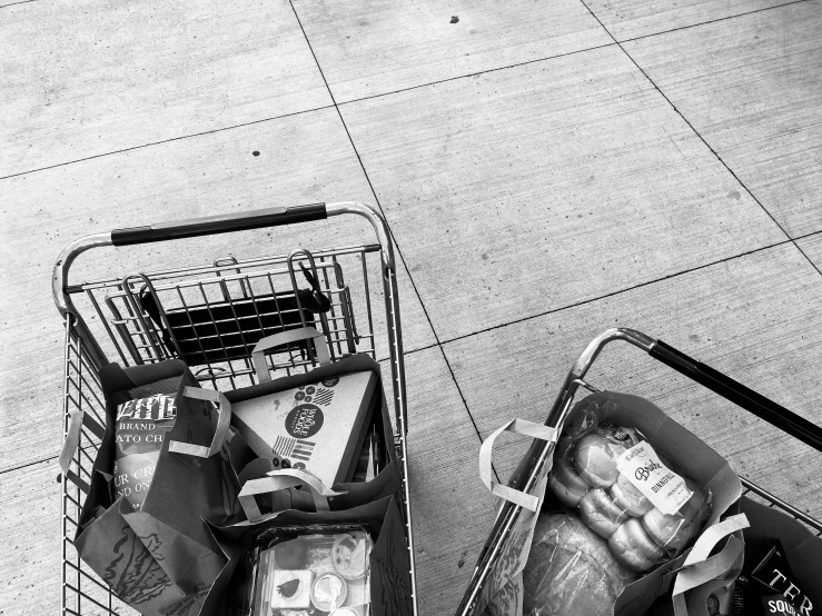 a shopping cart on the sidewalk with two baskets full of food