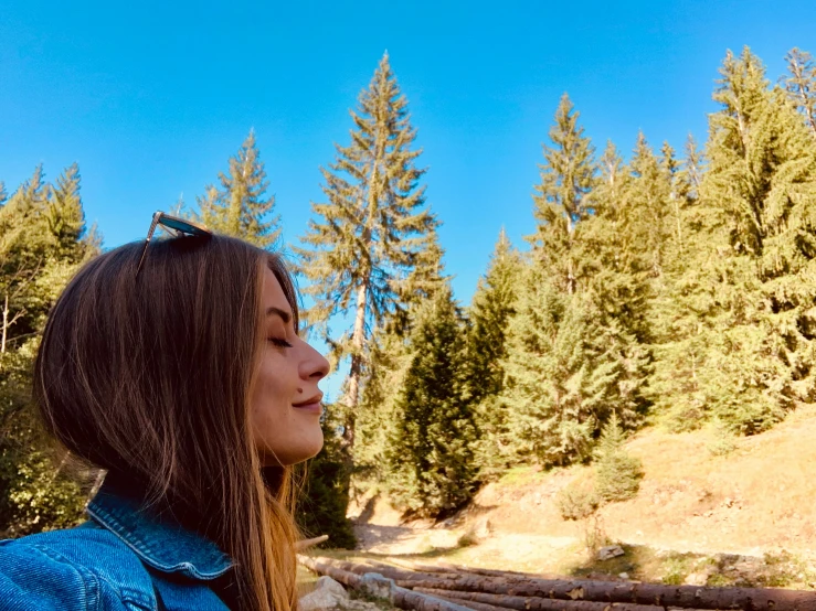 a girl in the woods with a blue jean jacket on