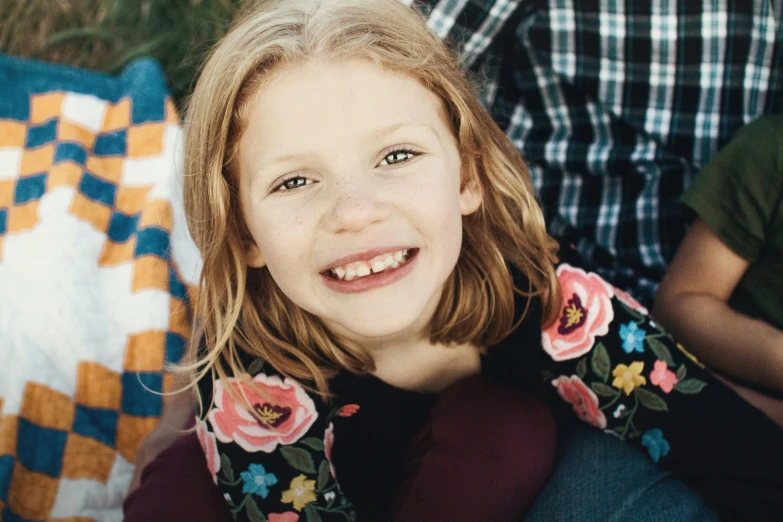 an adorable little girl smiling in front of some quilts