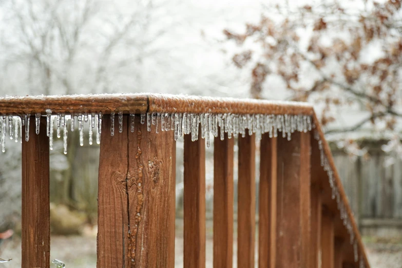 icicles on top of a wooden railing during the winter