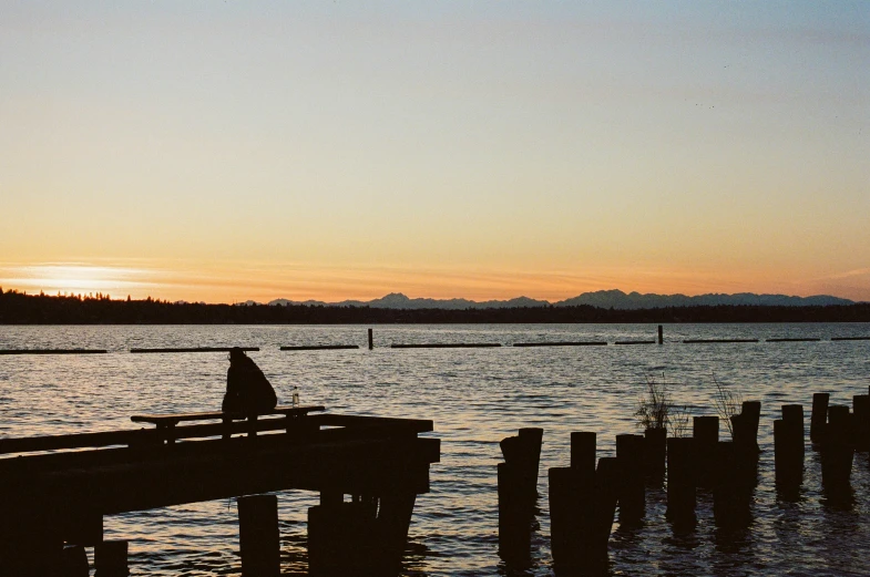 silhouette of a person sitting on a pier