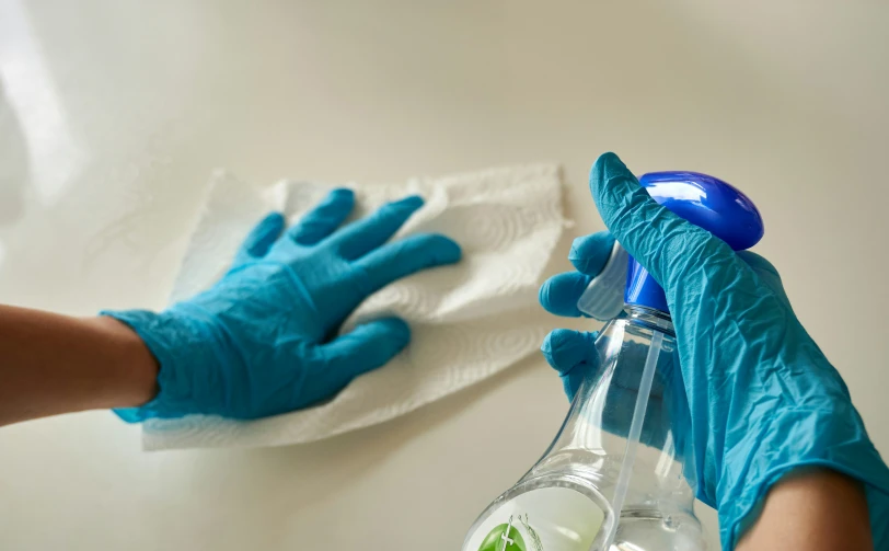 the cleaning glove on the table has the plastic bottle with a liquid in it