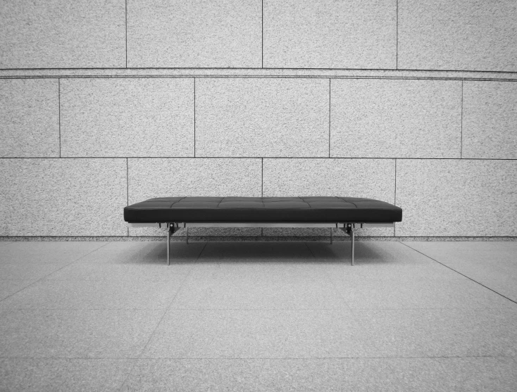 a bench is sitting against a wall with some light shining through it