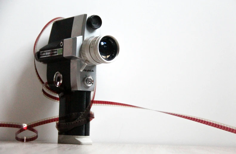 a black and white camera on a red ribbon