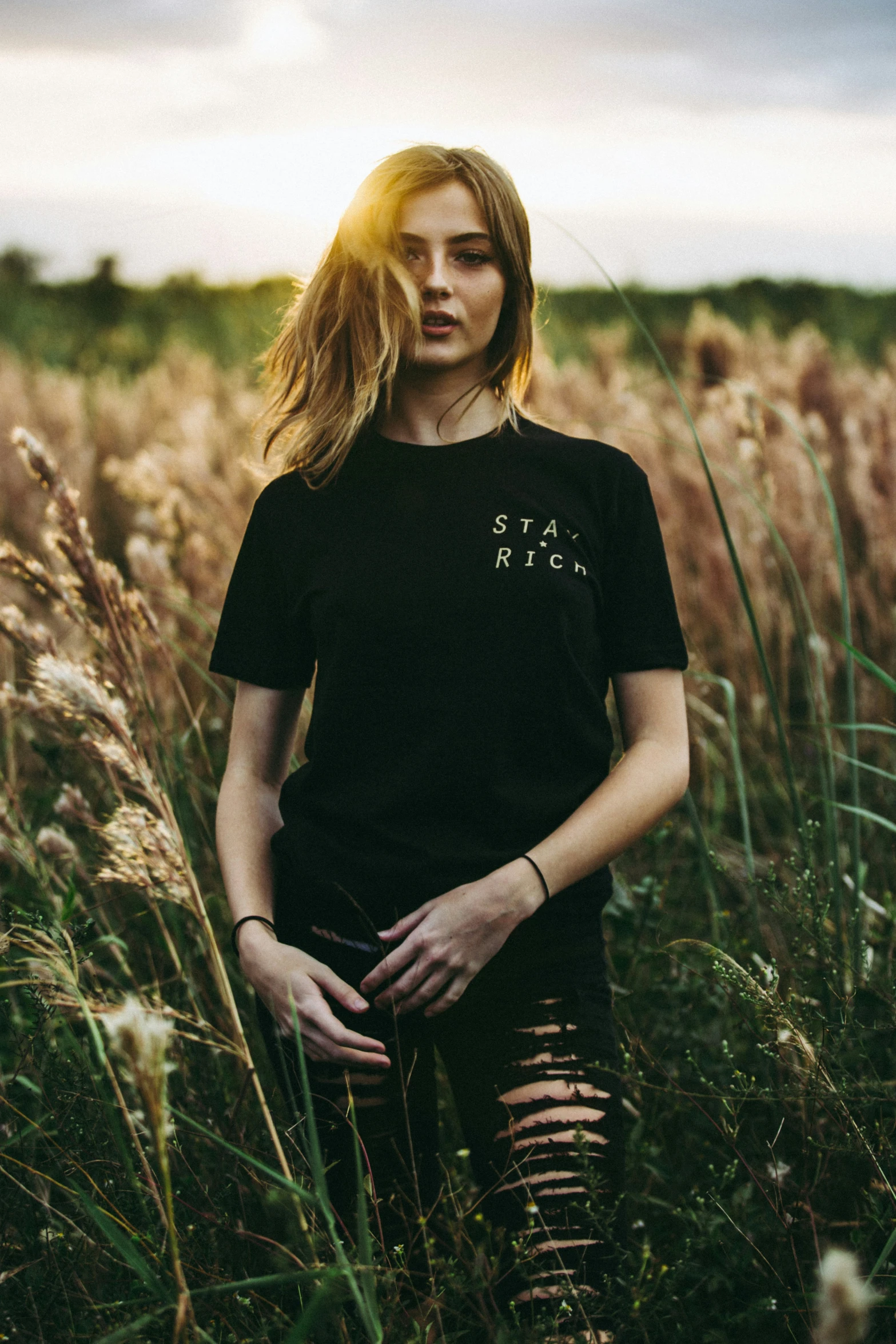 a woman in a black shirt standing outside by the grass