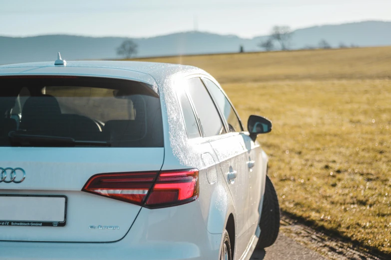 a white car driving down a road near the grass