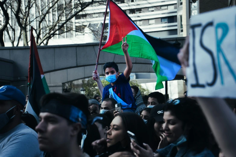 a crowd of people holding up flags and wearing masks