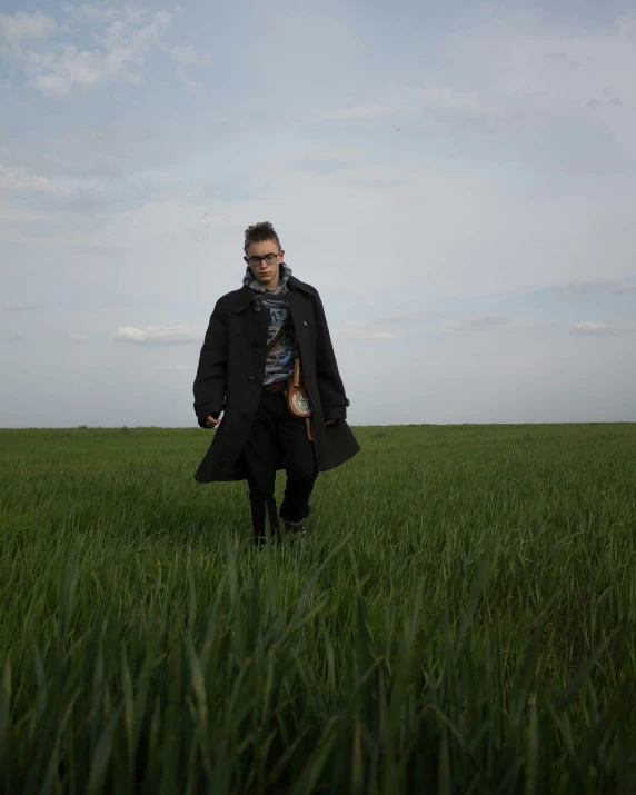 man in trench coat standing in grassy field