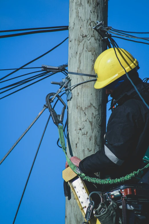 a worker is hanging on to an electric pole