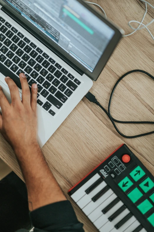 an electronic keyboard beside someone using their laptop