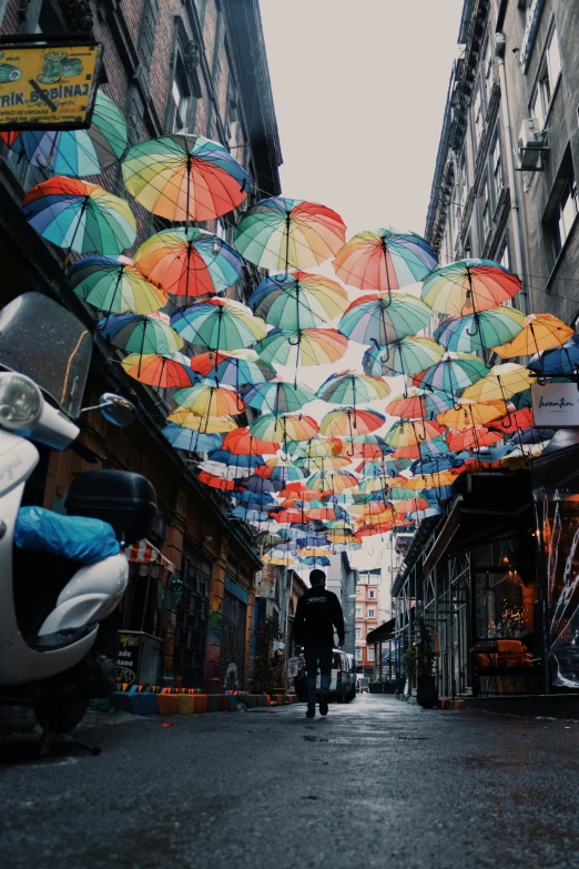 people walking down a street with umbrellas hanging from the side of buildings