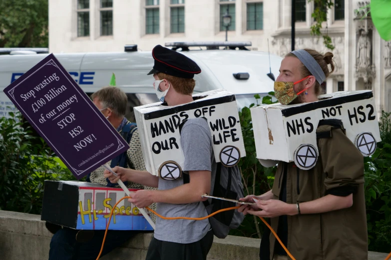 a few people with protest signs by some cars