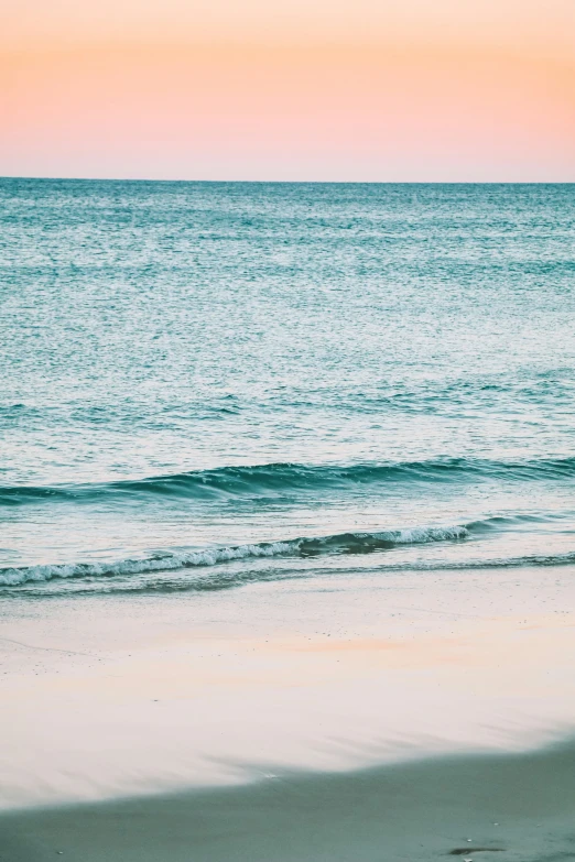 a person walks along a beach as the sun sets