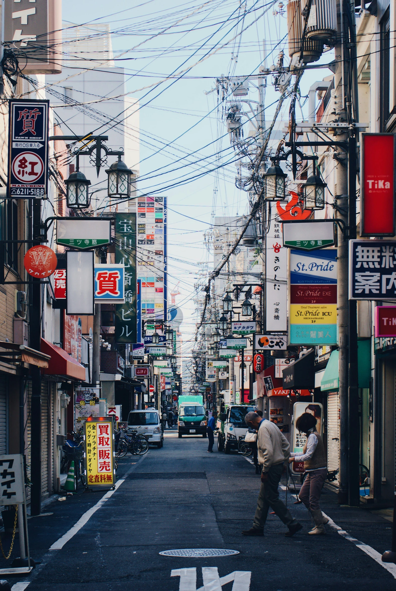 an asian street with cars, signs, people and a person holding an umbrella