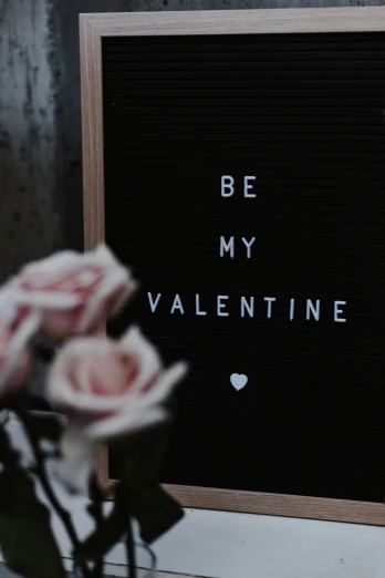 a valentine's card written on a black surface with roses