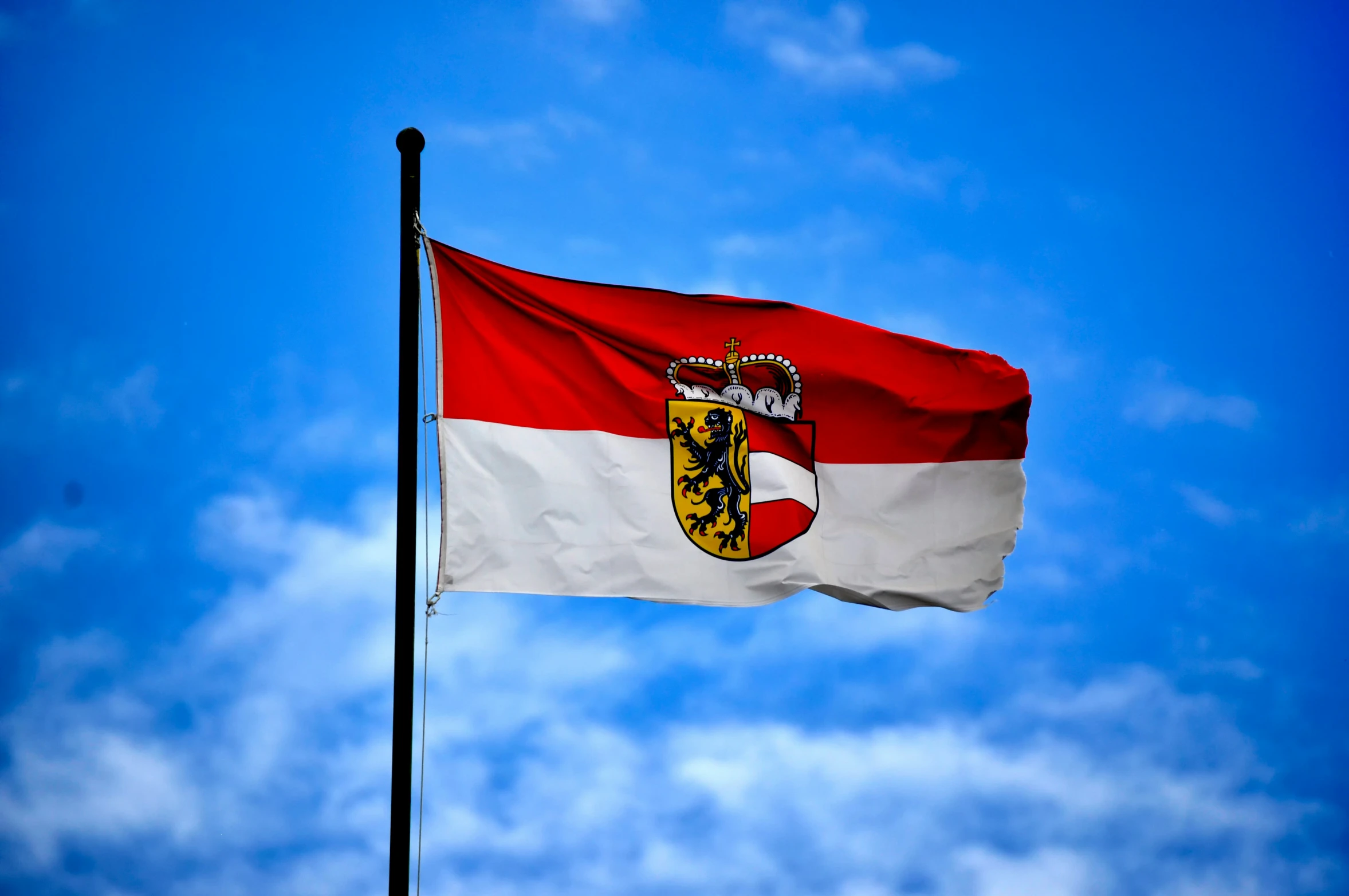 a flag waving in the wind against a blue sky