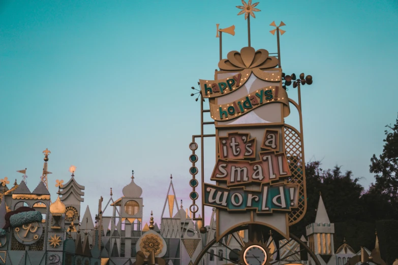 a disneyland world sign and it's small world at dusk