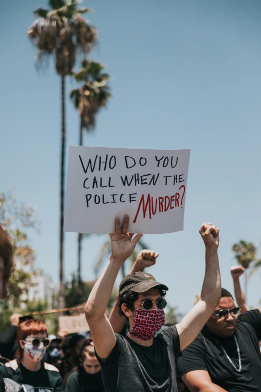 protesters hold signs reading who do you call when the police murder?