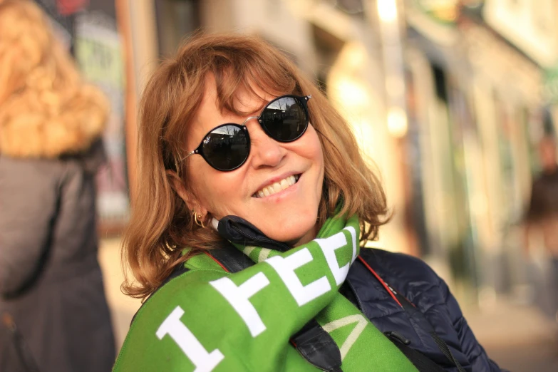 a woman standing on a city sidewalk in her sunglasses