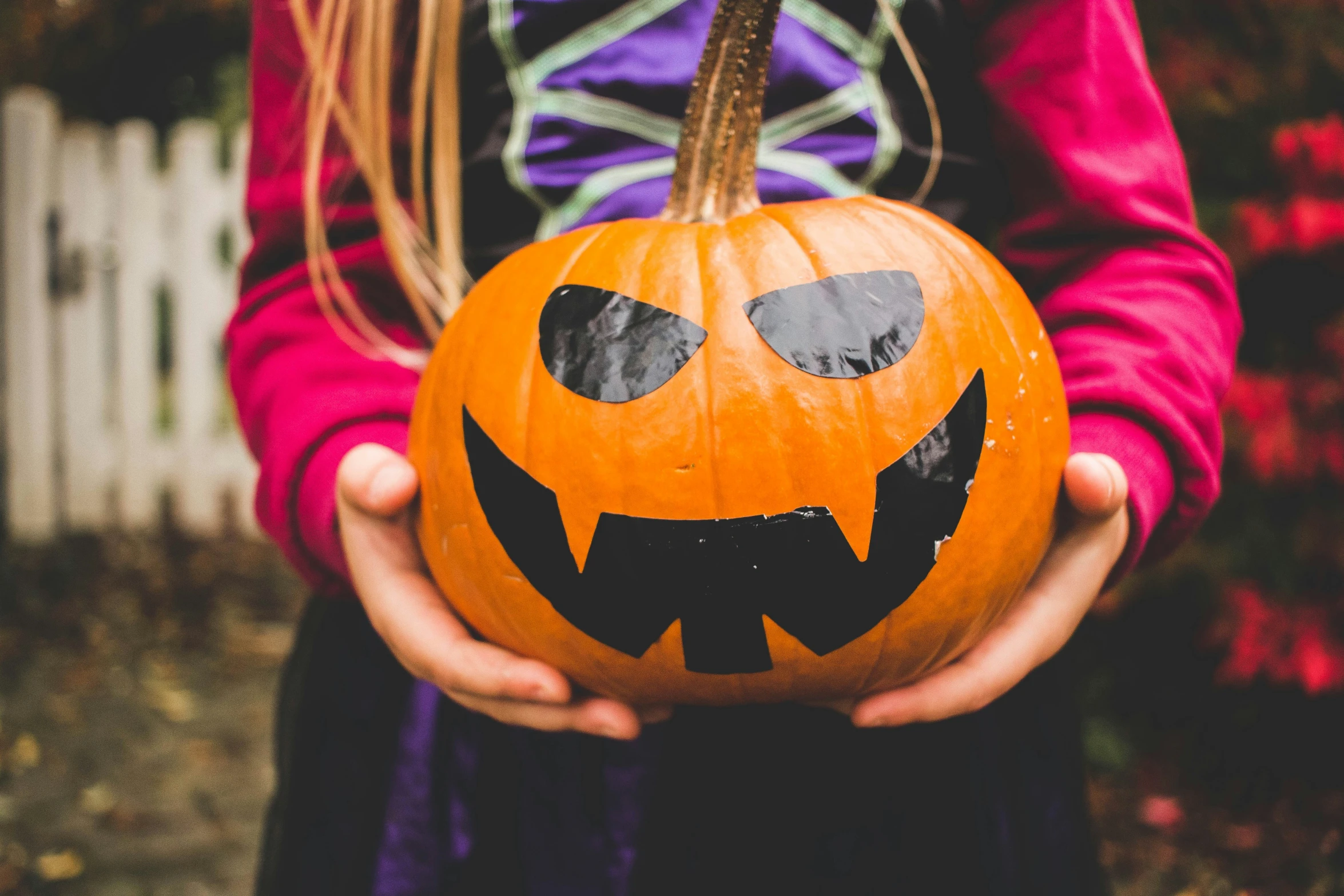 a person holding up a pumpkin that has faces painted on it