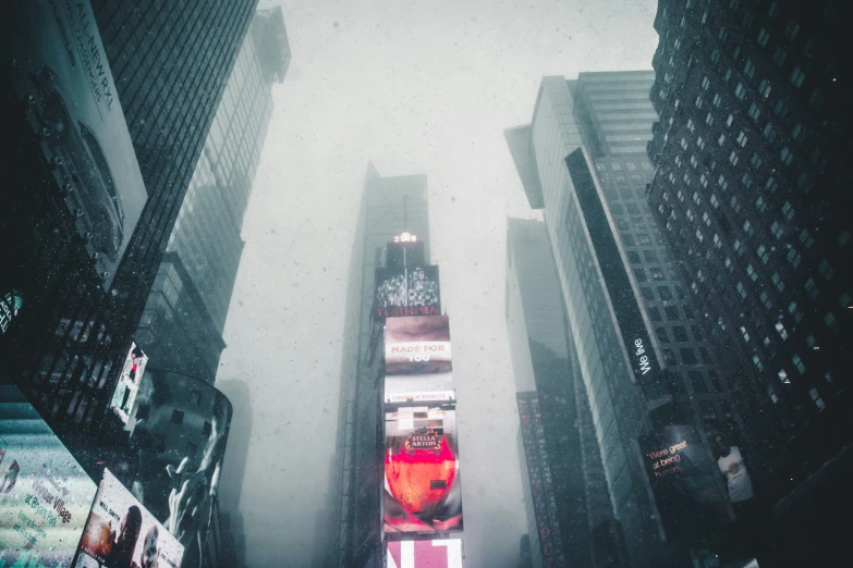 tall buildings on either side of a wet street are covered in rain