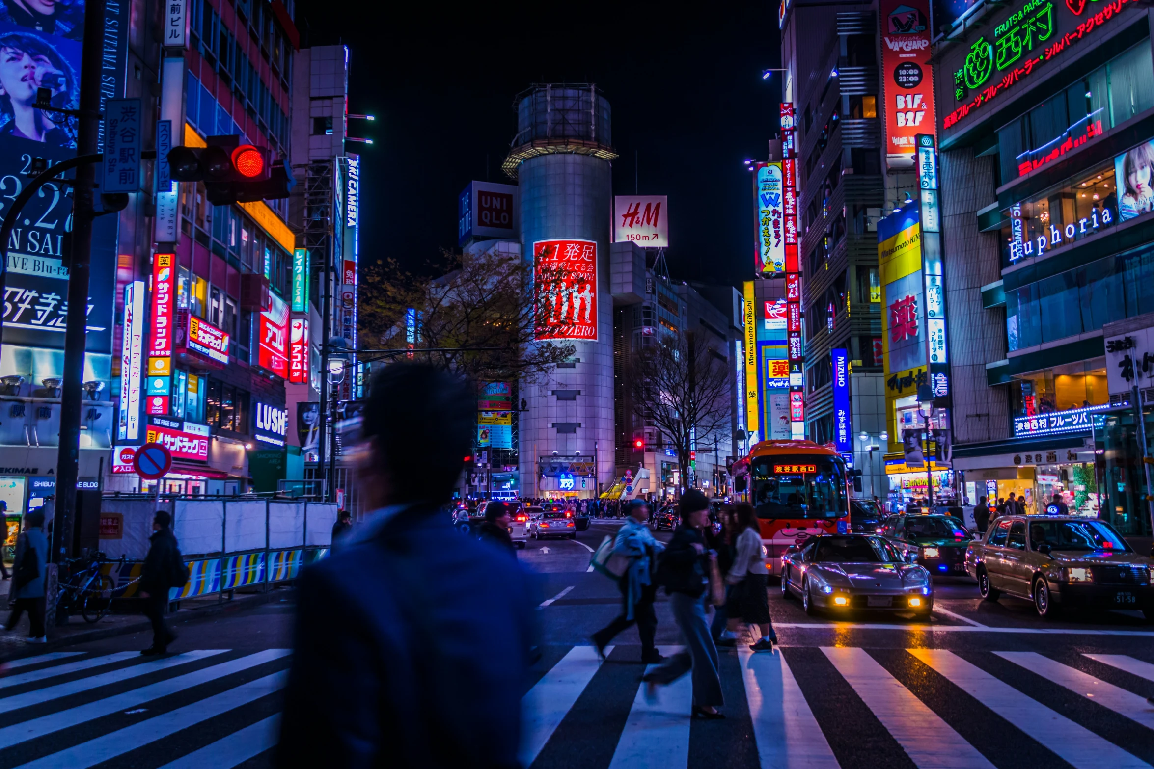 the people are crossing the city street at night