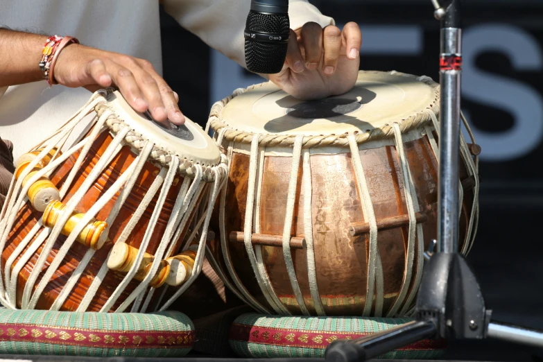 a man holding a microphone to a drum with other drums