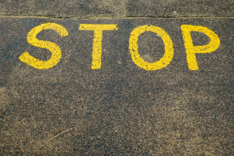 the word stop written on a street with yellow painted lines