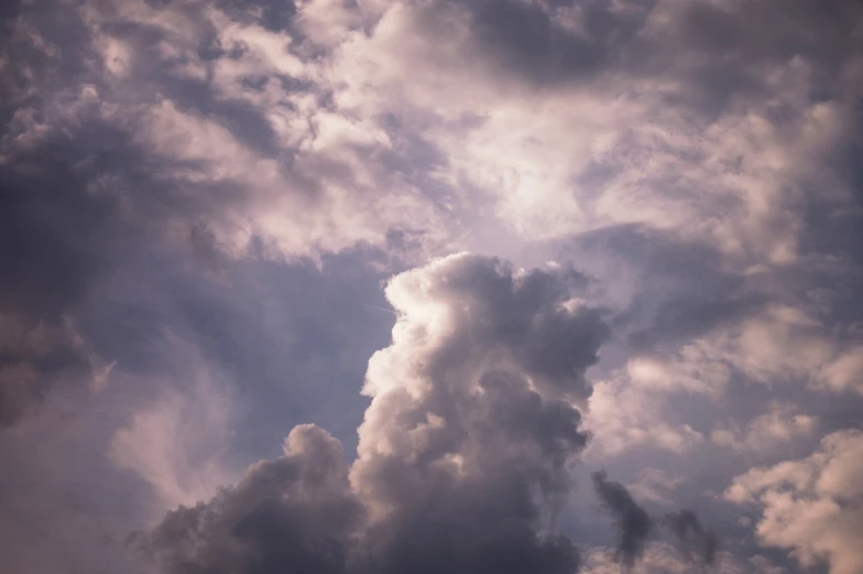 several clouds float around in the sky with a plane