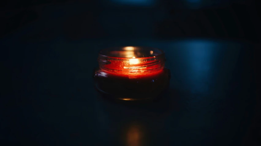 a lit candle on the ground in a dark room