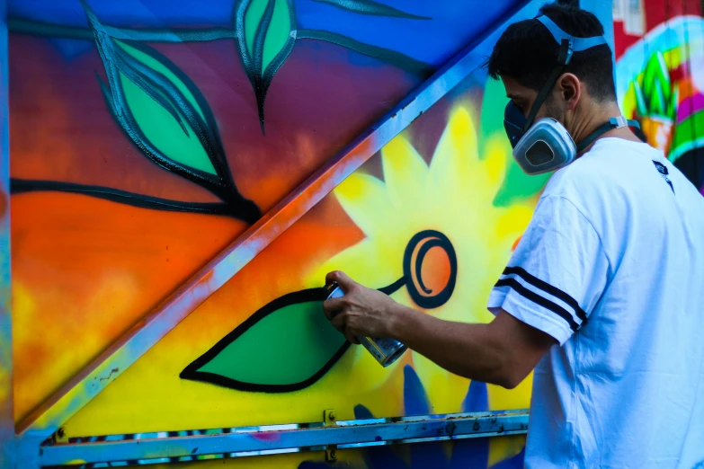 a man spray paints on a brightly painted wall