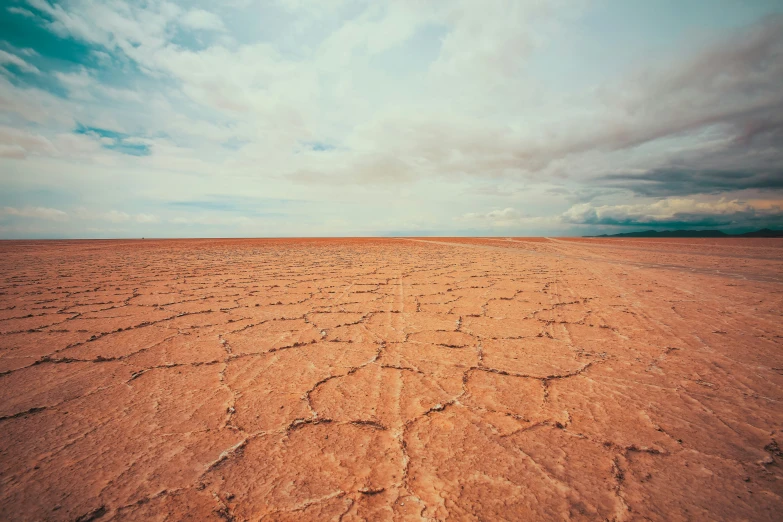 a large barren plain covered in mud under a cloudy sky