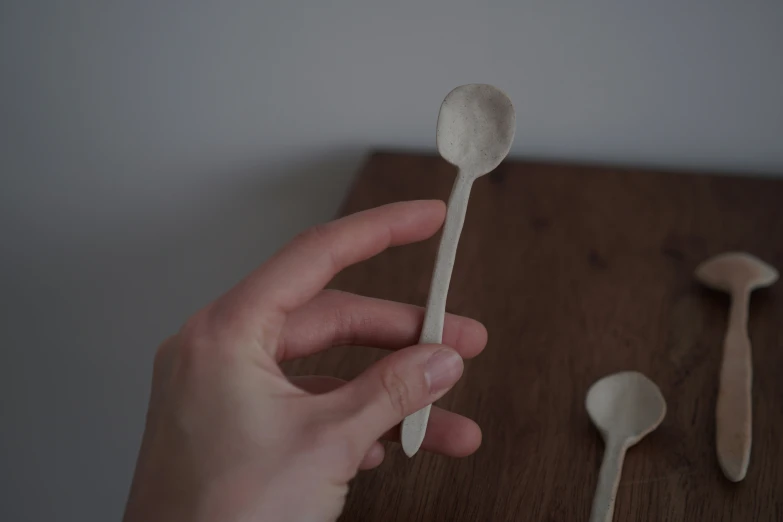 a hand holding a spoon over a wooden  board