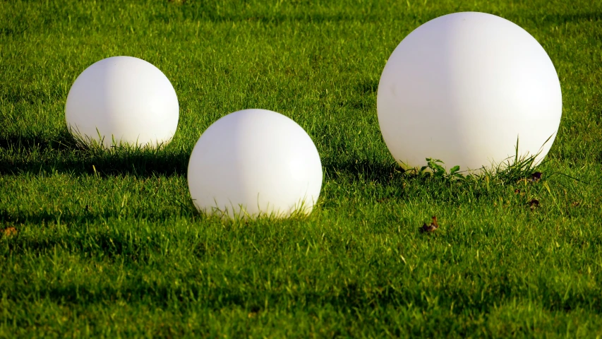 three white eggs sitting in the grass near each other