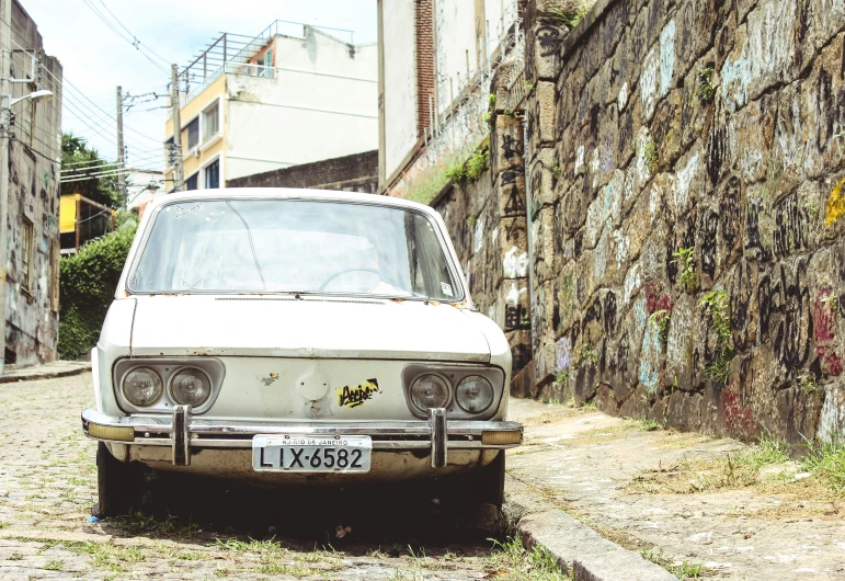 an old white car parked on the side of the street