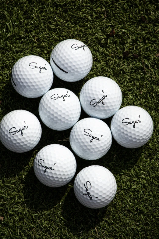 nine golf balls on green grass with autographed names